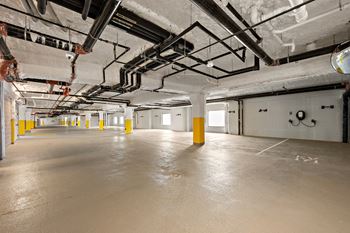 A large, empty warehouse with yellow bollards and exposed pipes.